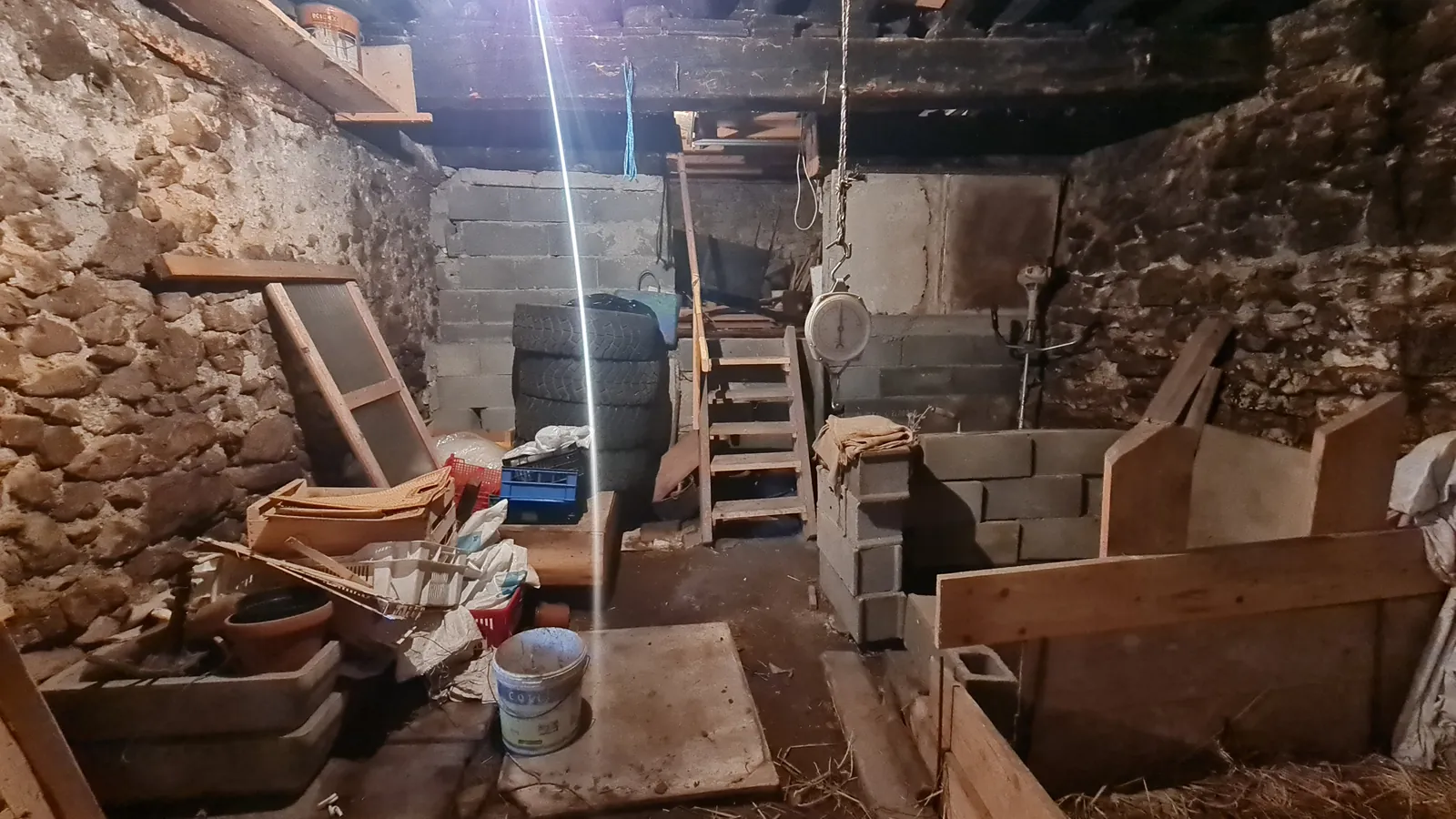 Avant · Un espace de stockage entre murs de pierre et plancher en bois.